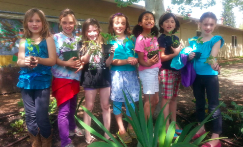 students posing for photo holding potted plants